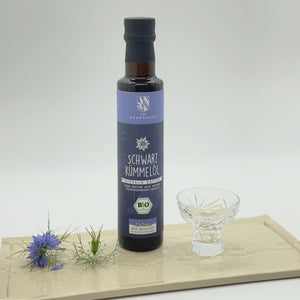 Eine Flasche Schwarzkümmelöl wird in ein Glas gefüllt